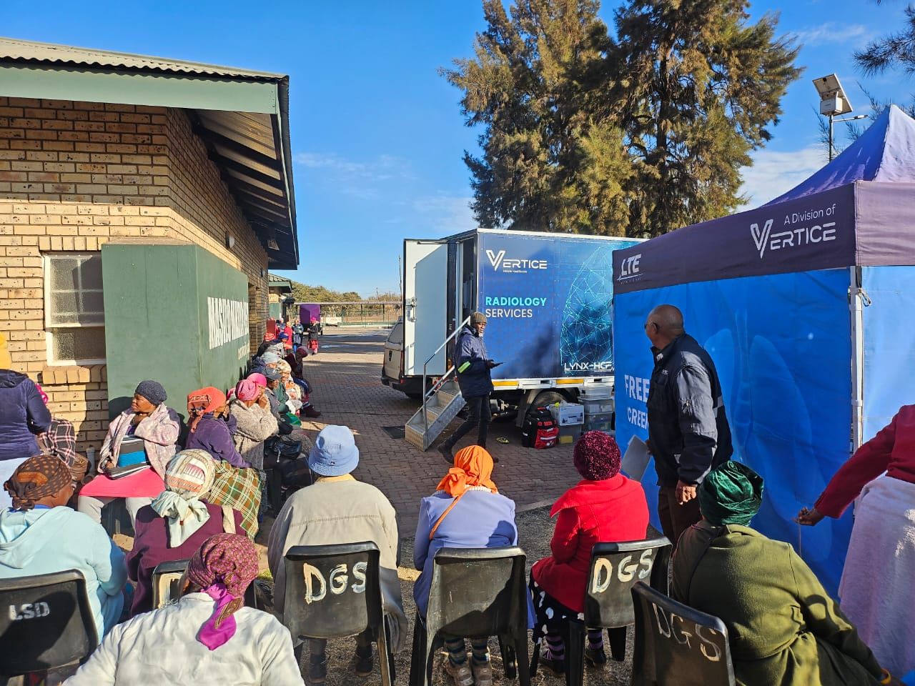 A Vertice Mobile Health outreach unit and community members waiting for integrated screening services at a rural site